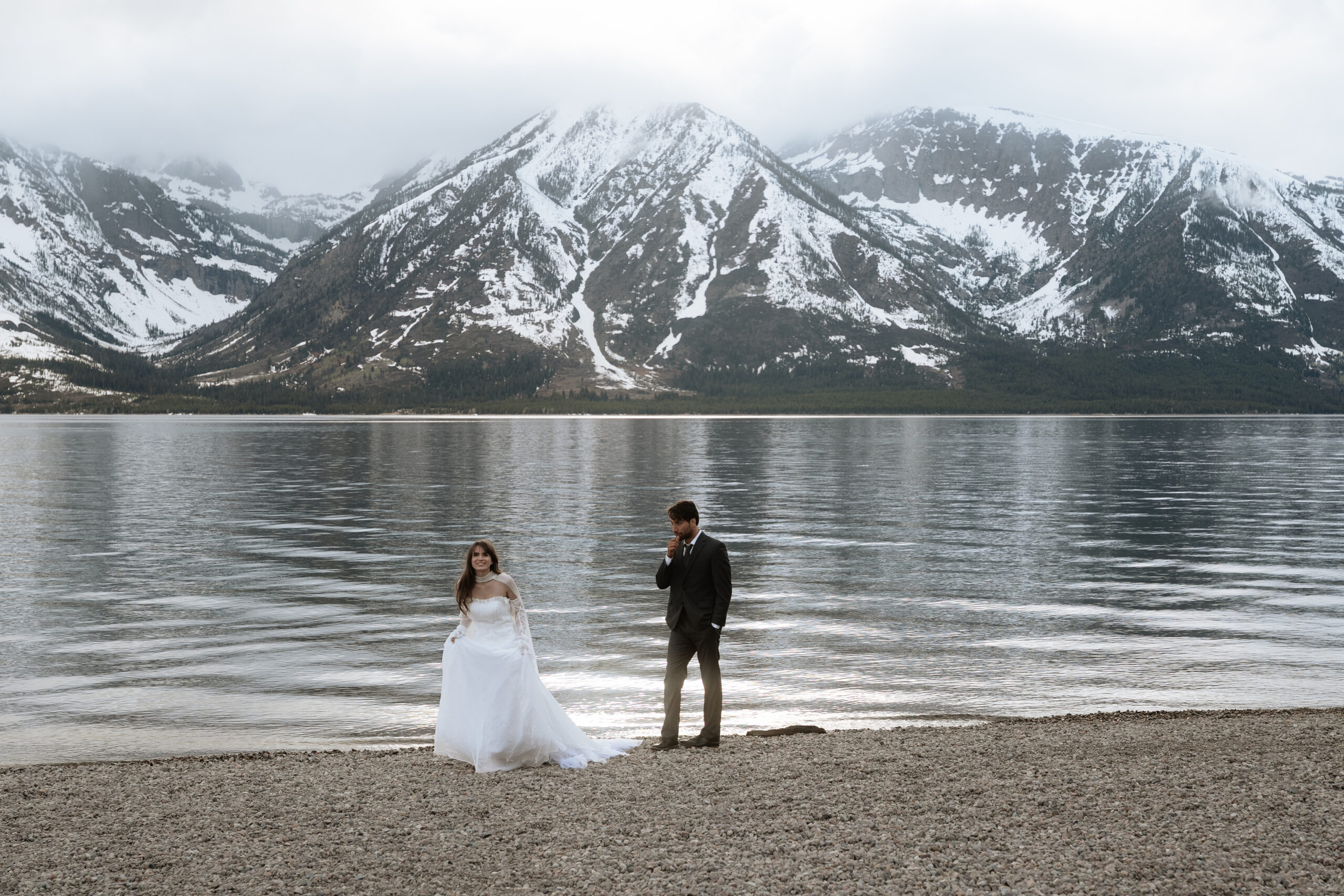 bride and groom elopement running across Colter Bay in Grand Teton National Park